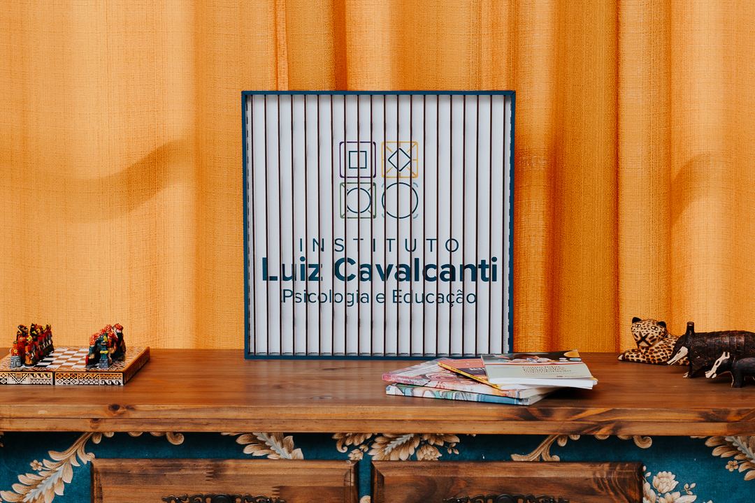 Placa do Instituto Luiz Cavalcanti sobre um móvel de madeira, diante de uma cortina dourada