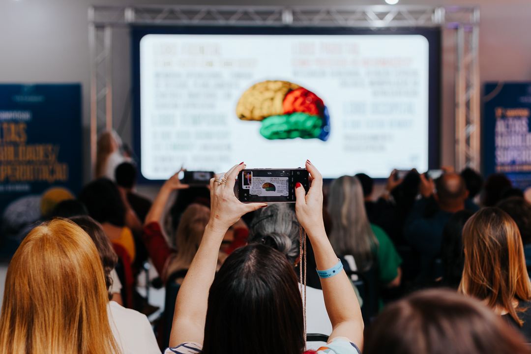 Participante fotografando um slide sobre o cérebro durante o simpósio